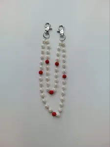 Detailed view of beaded chain with white rose patterns and red rhinestone balls