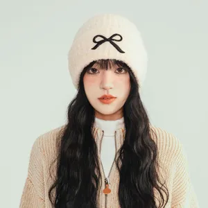 Detail view of women's autumn winter knit beanie hat with cute black bow, cozy warm pullover cap.