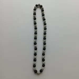 Detailed view of the black and silver rhinestone Shamballa clay bead necklace flat lay.