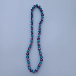 Close-up detail of sparkling blue and purple rhinestone clay bead necklace texture.
