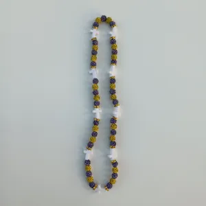 Close-up detail of the sparkling purple and gold beaded strand with white cross charms.