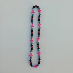 Detailed close-up of colorful crystal disco ball and pink cross beaded fashion necklace accessory.
