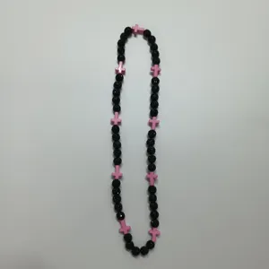 Detail view of a hip-hop style Shamballa beaded necklace with black balls and pink cross accents.