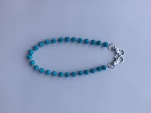 Macro detail of blue rhinestone clay ball trouser chain with silver metal clasps