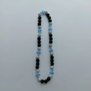 Detailed close-up of the beaded necklace featuring black, silver diamond, and blue cross charms.