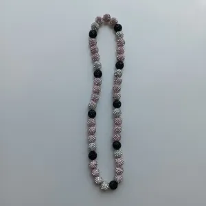 Close-up detail of sparkling rhinestone clay bead necklace in black, silver and pink tones.