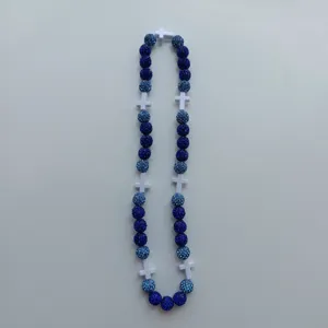 Close-up view of blue crystal rhinestone shamballa beads and white cross necklace details.
