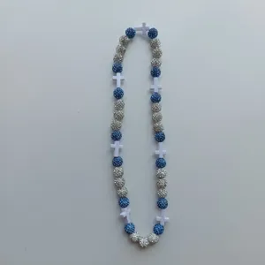 Detailed shot of a stylish beaded necklace featuring blue and silver pavé beads and white cross charms.