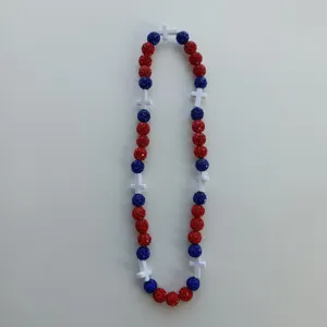 Closeup view of the red and blue rhinestone shamballa bead necklace featuring white cross spacers.