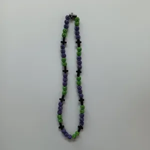 Detailed view of the sparkling purple and green clay rhinestone bead necklace with black cross charms.