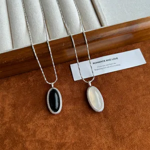 Detailed view of elegant black and white agate oval pendants on silver twisted chains