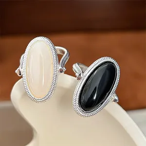 Close-up of elegant silver wire wrapped rings with black onyx and cream stones.