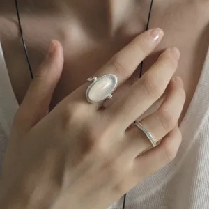 Elegant silver wire wrapped ring with oval moonstone worn on hand with a thin band.