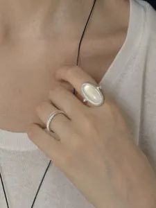 Close-up of minimalist silver band and elegant oval moonstone ring set worn on hand