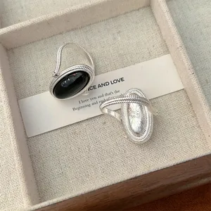 Close-up detail of a silver wire wrapped ring featuring a polished oval black onyx stone