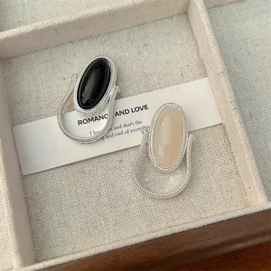 Detail view of rotatable silver wire wrapped rings with black onyx and beige stones