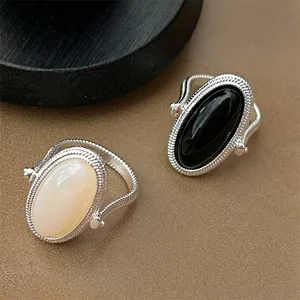 Close-up detail of black onyx and white shell rings with silver-tone wire wrapped design