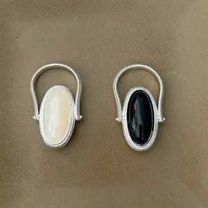 Detail shot of two silver-tone rings with black onyx and white oval gemstones.