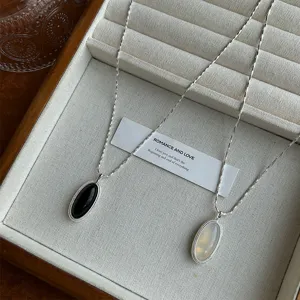 Close-up detail of two elegant oval gemstone pendants on silver chains in a display tray