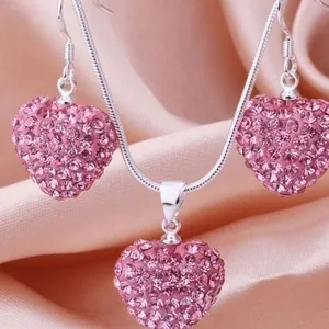 Detailansicht von rosa Kristallherz-Anhänger und Ohrringen an Schlangenkette
