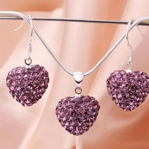 Detailaufnahme eines versilberten Herz-Schmucksets mit lila Strasssteinen besetzt