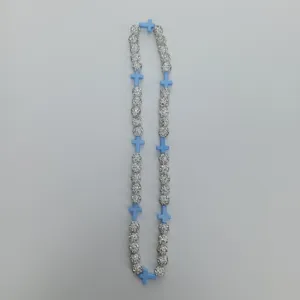 Detail shot of the rhinestone paved ball beads and light blue cross necklace accessory strand.