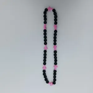 Detail view of black beaded necklace featuring pink cross charms for a unique hip hop style.