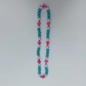 Close-up detail view of rhinestone disco balls and pink cross beads necklace pendant.