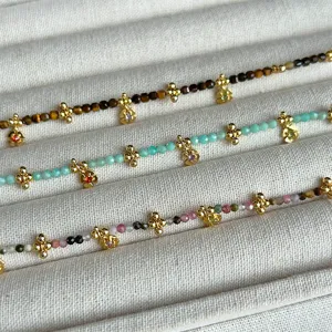 Primer plano de collares de cuentas de piedra natural con colgantes de flores de oro