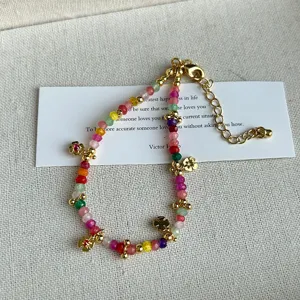 Primer plano de un collar de turmalina de colores con dijes de trébol de cuatro hojas
