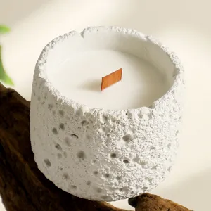 Handmade soy wax scented candle in textured white concrete container with wooden wick.