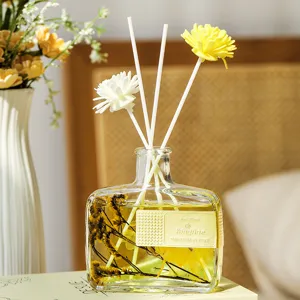 Diffuseur de roseaux en bouteille de verre plat avec fleurs immortelles et huile parfumée.