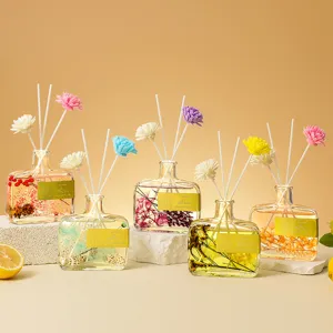 Diffuseur de roseaux à fleurs conservées en bouteille en verre plat avec huile et bâtonnets.