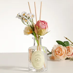 Aromatherapy reed diffuser with glass bottle, wooden sticks and artificial flowers for home decor.