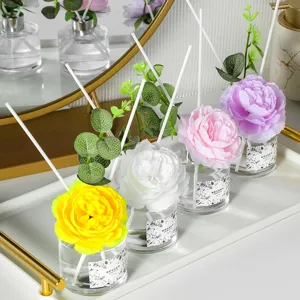 Set difusor de aromaterapia floral decorativo con botellas de vidrio y peonías artificiales.