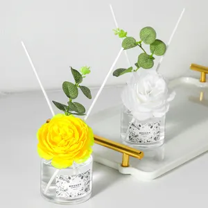 Set difusor de aromas con flores amarillas y blancas, botellas de vidrio y bandeja dorada para el hogar.