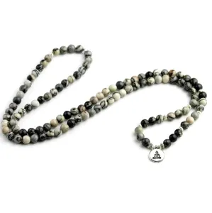 Primo piano dettagliato di collana mala con perle di pietra e ciondolo buddha in argento.