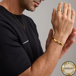Close-up of minimalist gold-plated stainless steel open bracelet and ring on male model