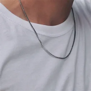 Close-up of minimalist stainless steel silver box chain necklace worn on a white t-shirt