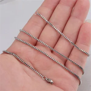 Close-up detail of a slim silver stainless steel box chain necklace held in hand