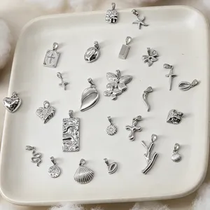 Sammlung verschiedener Anhänger aus Edelstahl mit Herz-, Schmetterlings- und Kreuzmotiven.