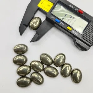 Detailed view of natural pyrite oval cabochon stones being measured with a caliper