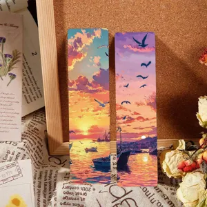Detalle de marcapáginas de papel creativos con atardecer romántico y paisaje marino.