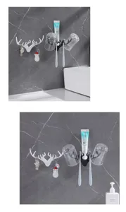 Detalle de ganchos de pared con forma de asta usados como portacepillos y vasos en el baño