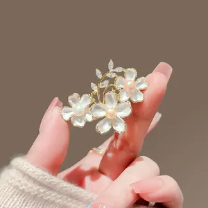 Dettaglio spilla fiore perla elegante con metallo dorato per cappotto vestito donna.