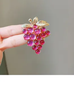 Detailed close-up of a sparkling purple grape brooch with gold leaves, exquisite accessory.