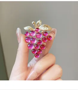 Detailed close-up of a charming purple grape brooch featuring gold leaves and sparkling beads.
