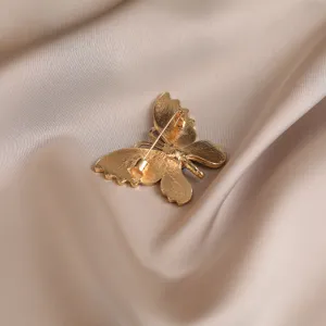 Detailed view of the gold butterfly brooch back showing secure pin clasp and fine metal texture.