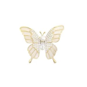 Détail de broche papillon exquise, cadre doré avec strass étincelants et perle élégante.