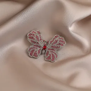 Primo piano sui dettagli della spilla a farfalla in strass scintillanti su tessuto satin.